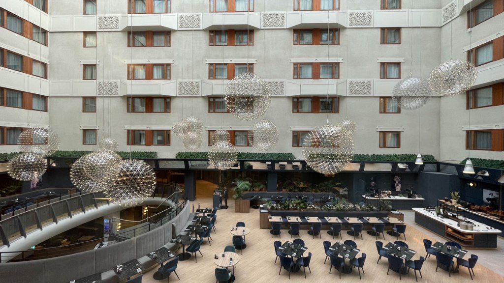 Frokostsalen sett ovenfra. Bord og store taklamper. Foto.